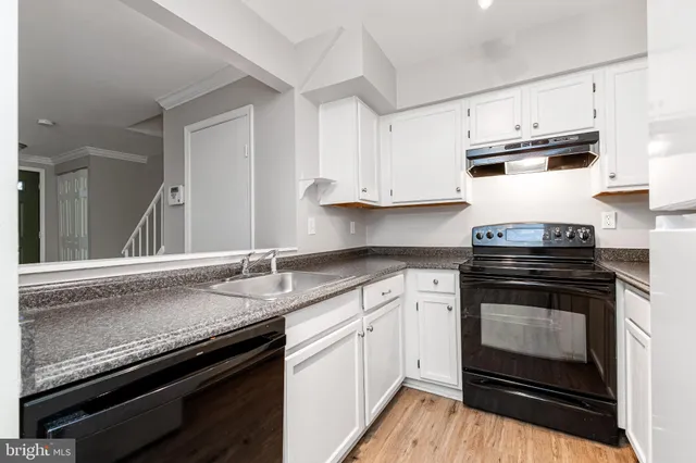 a kitchen with granite countertop a stove sink and cabinets