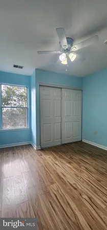 an empty room with wooden floor fan and windows