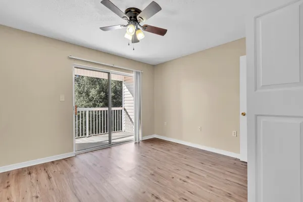 an empty room with wooden floor fan and windows