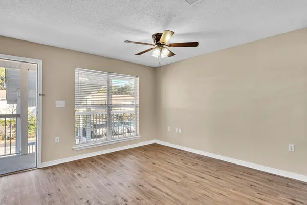 an empty room with wooden floor fan and windows