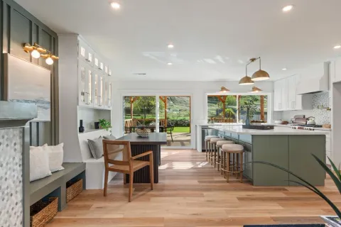 a kitchen with stainless steel appliances granite countertop a refrigerator a stove a sink dishwasher and a dining table with wooden floor