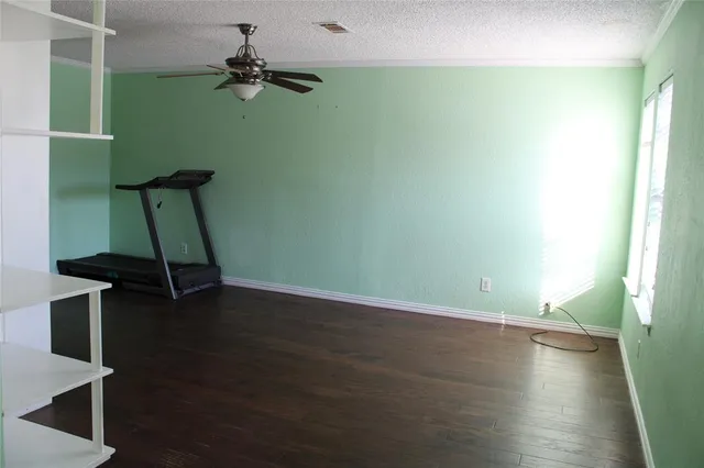a view of a room with wooden floor and a ceiling fan