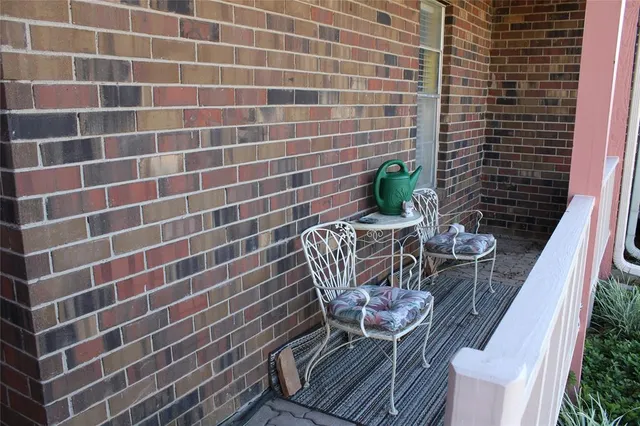 a view of a brick wall with a chair and table in the balcony