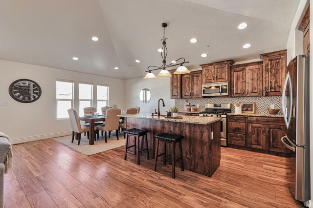 1288 North Horizon View Loop Elk Ridge, UT 84651 - Photo 10 of 40 Kitchen with stainless steel appliances, light stone counters, an island with sink, pendant lighting, and light wood-style floors