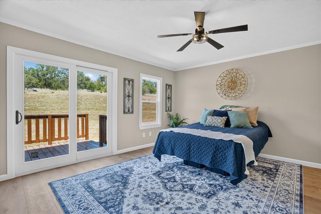130 R And R Drive Springtown, TX 76082 - Photo 17 of 40 Wood-finish flooring, ceiling fan with integrated lighting, sliding glass door to exterior deck, and large window