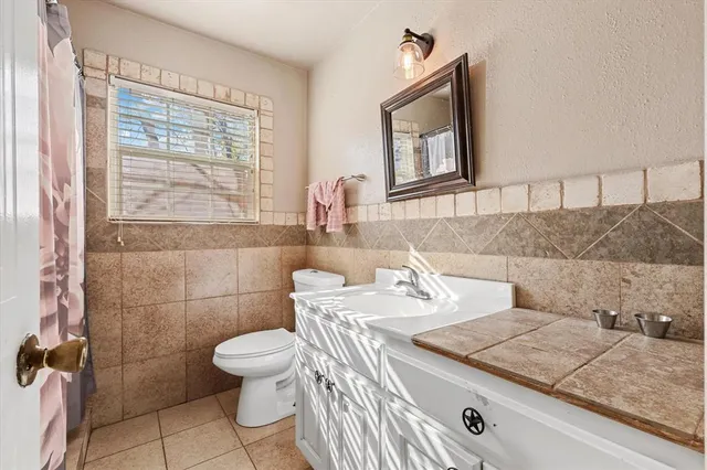 a bathroom with a granite countertop sink a toilet and mirror