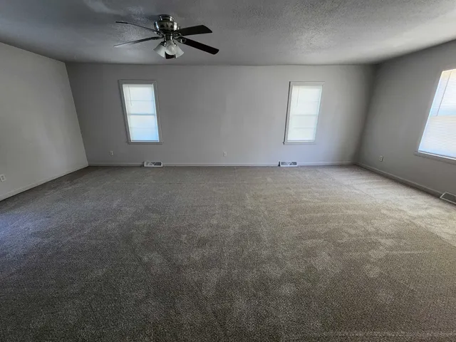 an empty room with windows and ceiling fan