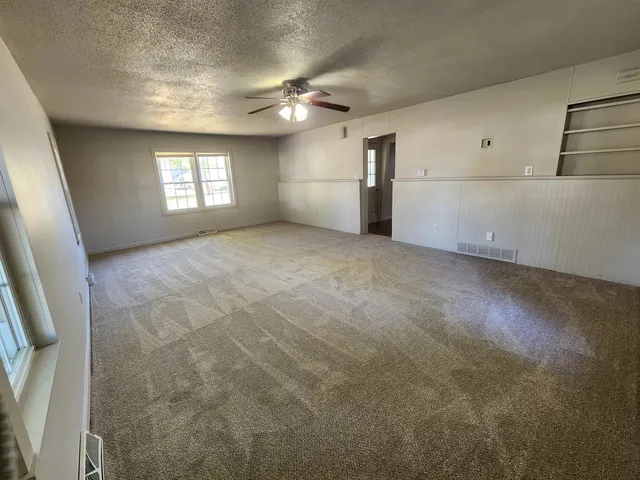 an empty room with windows and refrigerator