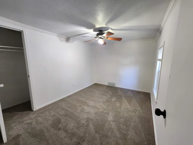 an empty room with a ceiling fan and a window