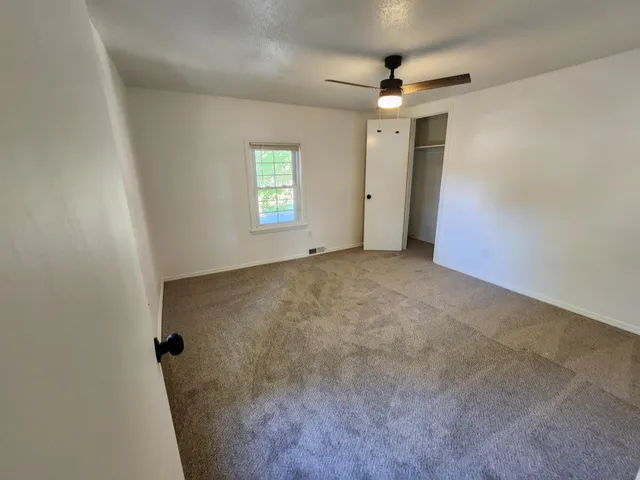 an empty room with windows and fan