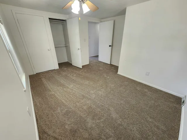 an empty room with a chandelier fan and wooden floor