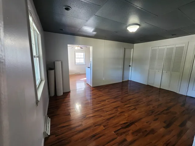 an empty room with wooden floor and windows