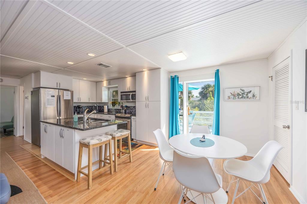 5075 North Beach Road, Unit B4 Englewood, FL 34223 - Photo 13 of 79 a kitchen with stainless steel appliances kitchen island granite countertop a refrigerator a stove a dining table and chairs with wooden floor
