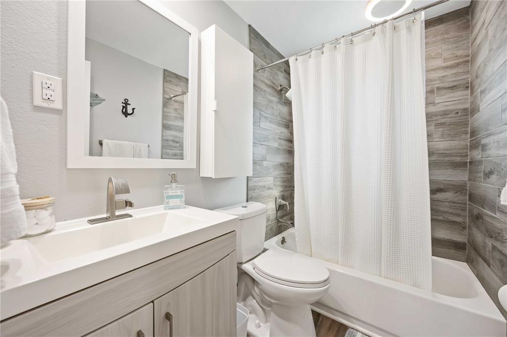 5075 North Beach Road, Unit B4 Englewood, FL 34223 - Photo 18 of 79 a bathroom with a sink a toilet a mirror and shower curtain