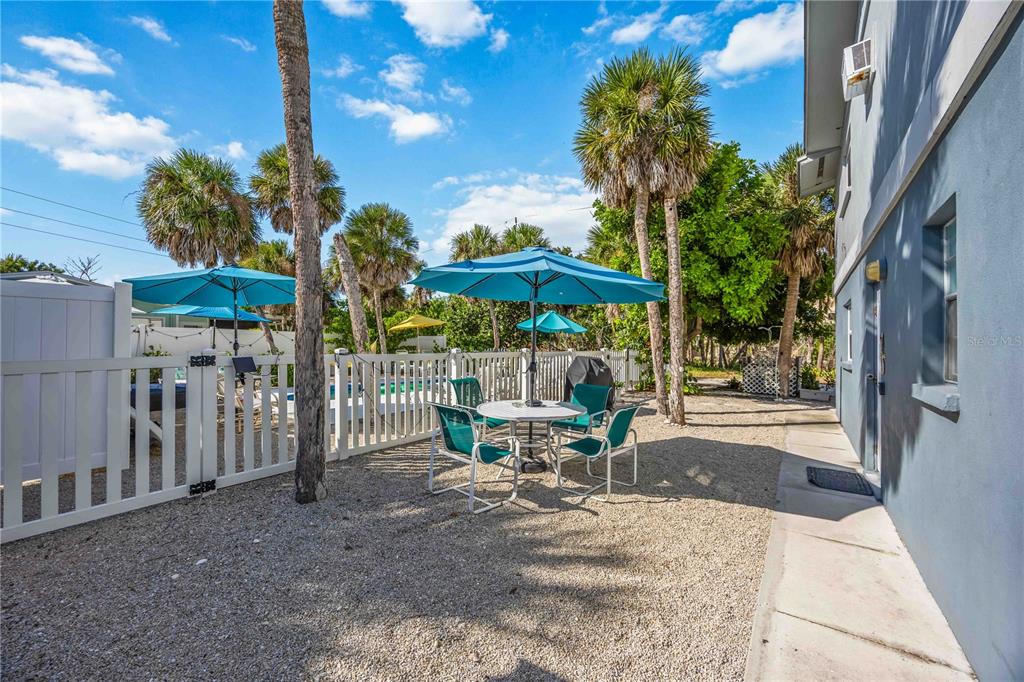 5075 North Beach Road, Unit B4 Englewood, FL 34223 - Photo 43 of 79 a view of a patio with a table and chairs under an umbrella with a small yard