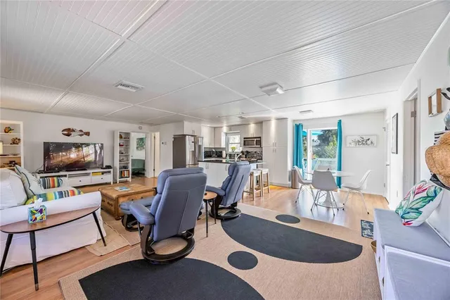 a kitchen with stainless steel appliances kitchen island granite countertop a refrigerator a stove a dining table and chairs with wooden floor