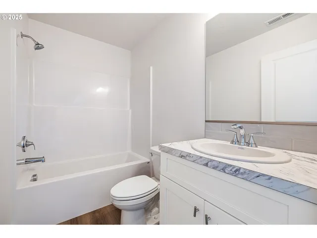 a bathroom with a granite countertop sink toilet a mirror and bathtub
