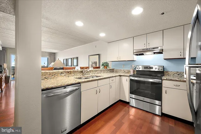 a kitchen with granite countertop white cabinets and white appliances
