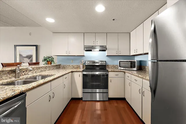 a kitchen with granite countertop white cabinets and white appliances