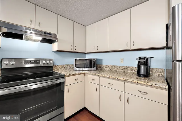 a kitchen with granite countertop white cabinets and appliances