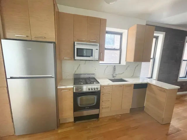 a kitchen with stainless steel appliances granite countertop a refrigerator a stove a sink and a microwave