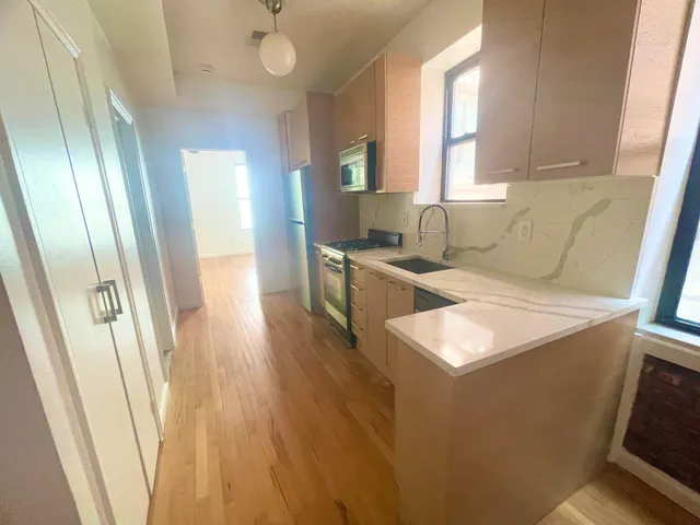 a kitchen with stainless steel appliances granite countertop a sink a stove a refrigerator a washer dryer and white cabinets