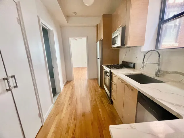 a kitchen with sink a refrigerator and wooden cabinets