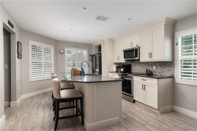 a kitchen with stainless steel appliances granite countertop a stove top oven a sink dishwasher a dining table and chairs with wooden floor