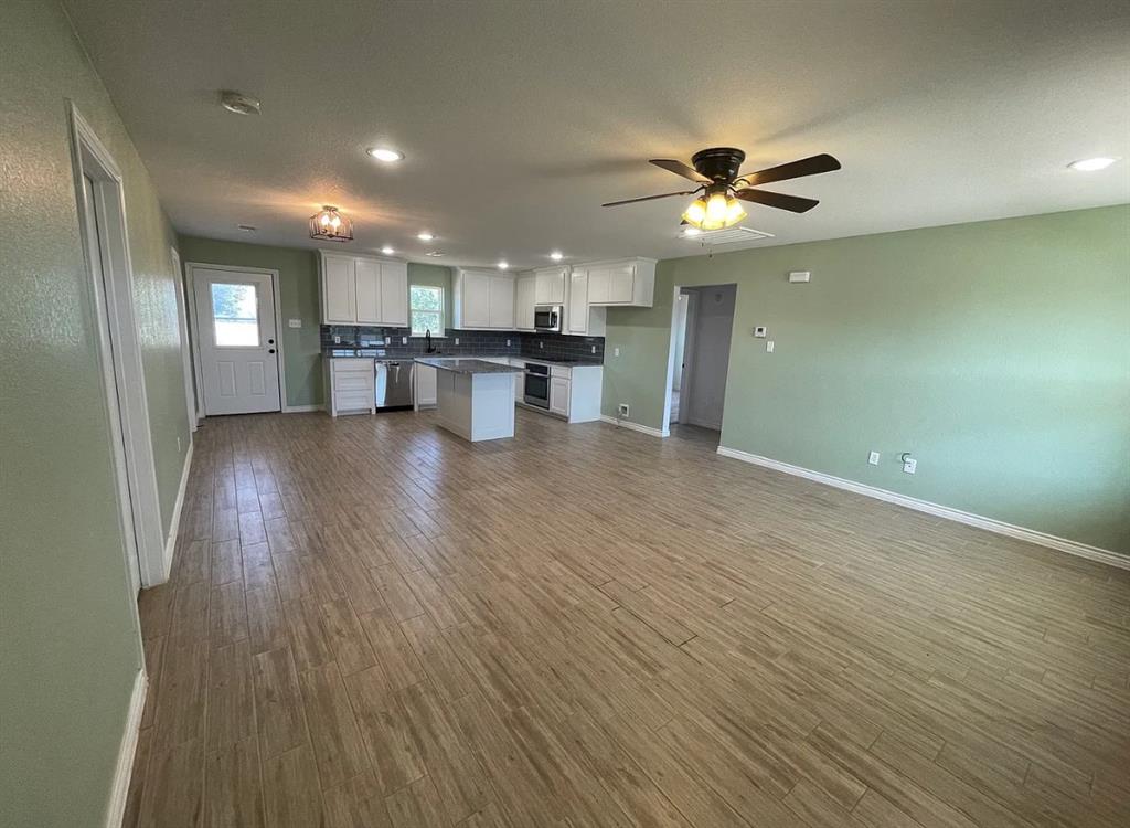109 Spruce Tree Court Poolville, TX 76487 - Photo 3 of 21 a view of an empty room with wooden floor and a ceiling fan