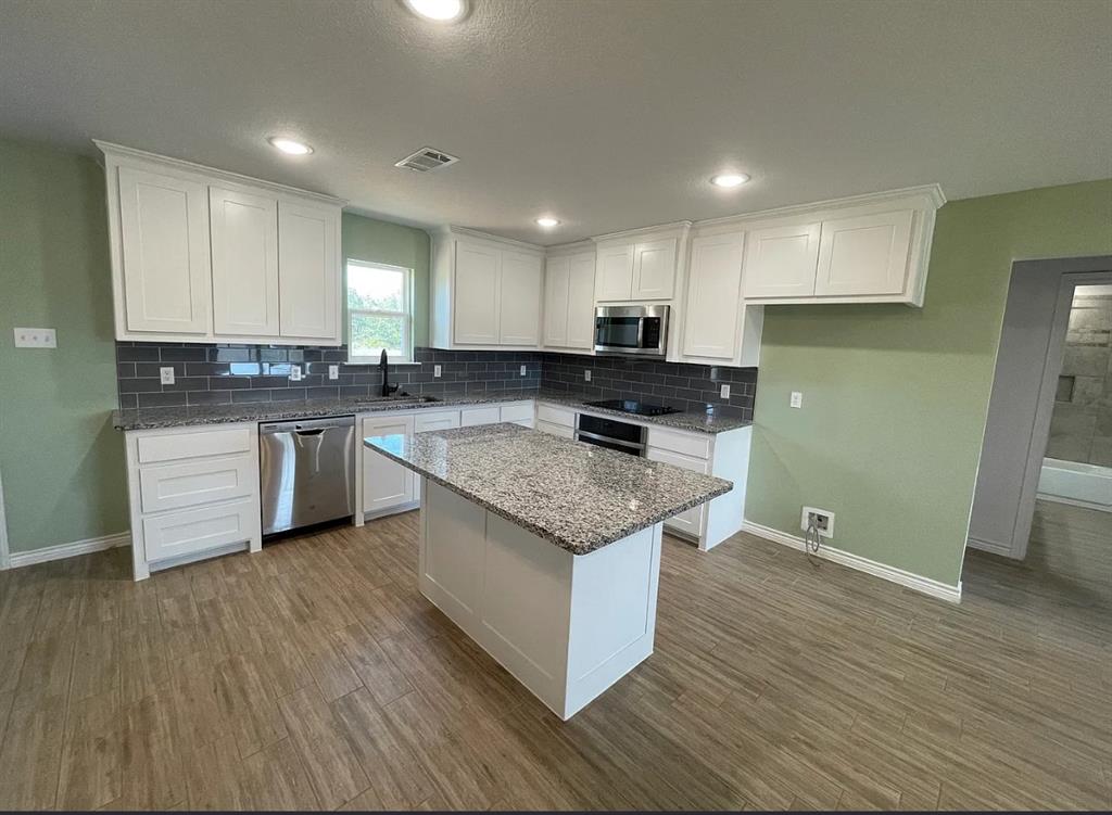 109 Spruce Tree Court Poolville, TX 76487 - Photo 6 of 21 a kitchen with stainless steel appliances granite countertop a stove a sink and a refrigerator