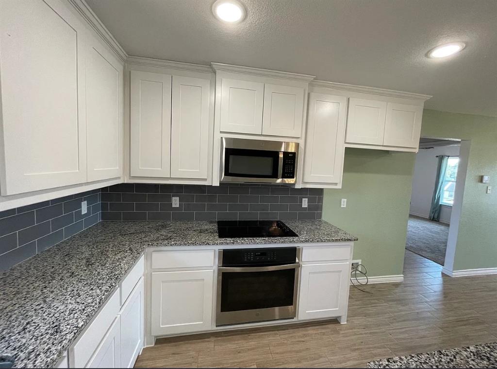 109 Spruce Tree Court Poolville, TX 76487 - Photo 8 of 21 a kitchen with granite countertop a stove and a sink