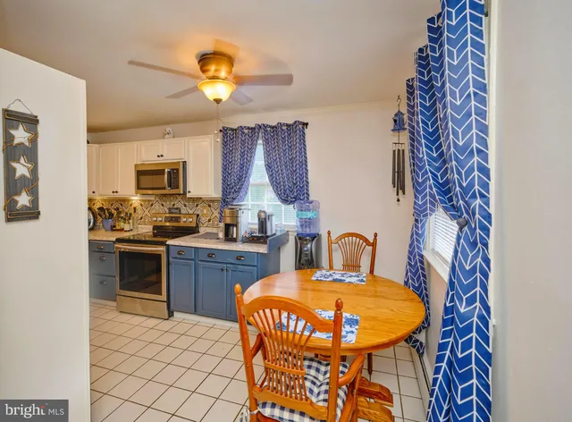 a kitchen with stainless steel appliances a stove a sink dishwasher a dining table and chairs with wooden floor