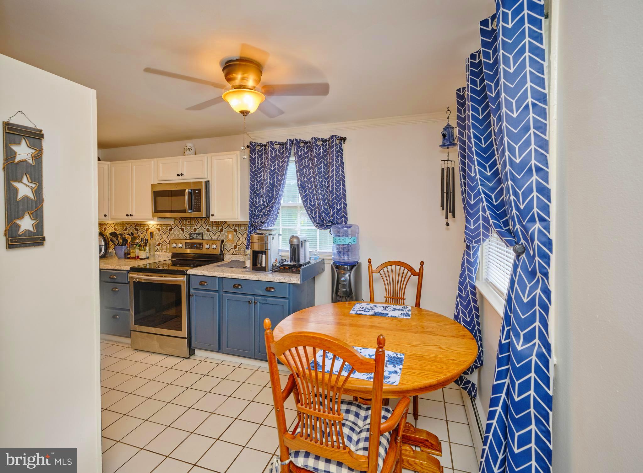 403 South Main Street, Unit S201 Doylestown, PA 18901 - Photo 5 of 13 a kitchen with stainless steel appliances a stove a sink dishwasher a dining table and chairs with wooden floor