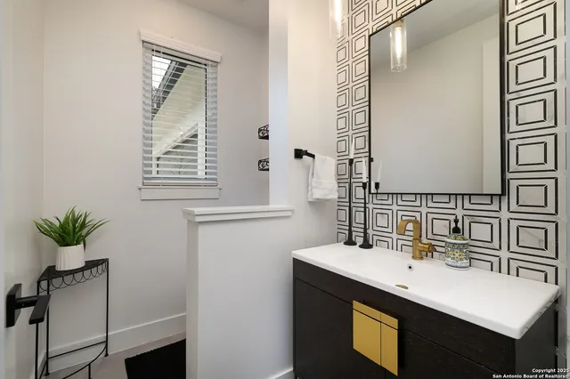 a bathroom with a sink a mirror and a potted plant