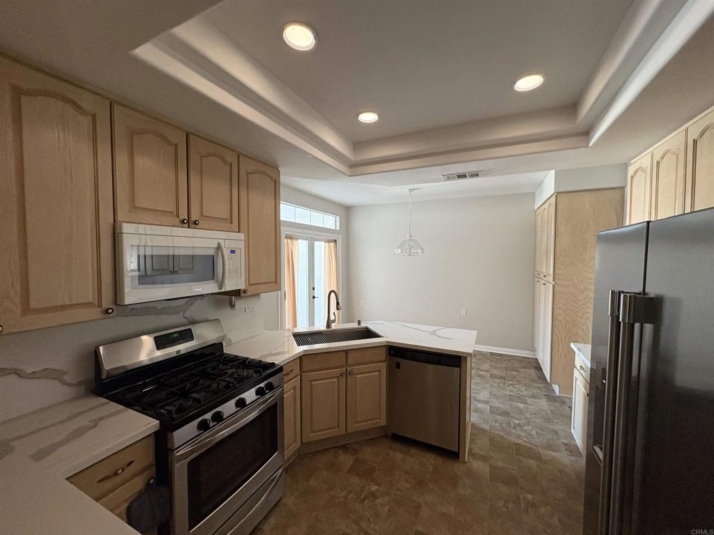 3365 Genoa Way, Unit 138 Oceanside, CA 92056 - Photo 14 of 34 a kitchen with stainless steel appliances granite countertop a stove a sink and a refrigerator