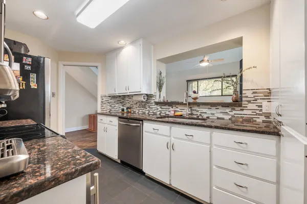 a kitchen with granite countertop a sink stove and cabinets