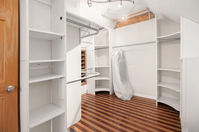a walk in closet with wooden floor