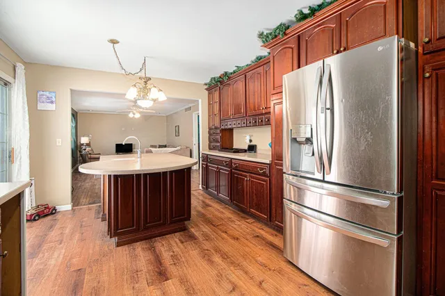 a kitchen with stainless steel appliances granite countertop a refrigerator a sink dishwasher a stove and a dining table with wooden floor