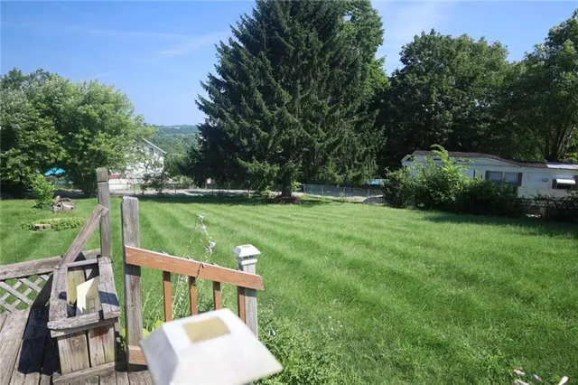 a patio with table and chairs and potted plants with wooden floor and fence