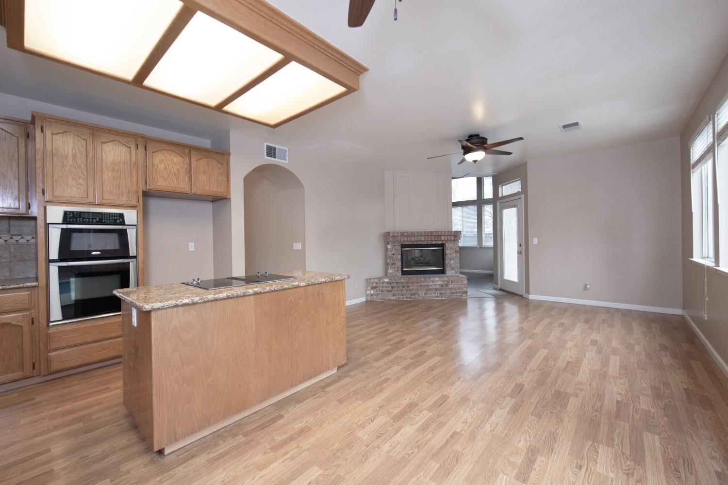 1361 Birch Avenue Clovis, CA 93611 - Photo 20 of 43 a kitchen with stainless steel appliances granite countertop a refrigerator a stove top oven a sink dishwasher and white cabinets with wooden floor