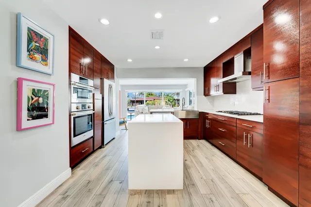 a kitchen with stainless steel appliances granite countertop a refrigerator a sink dishwasher and a stove with wooden floor