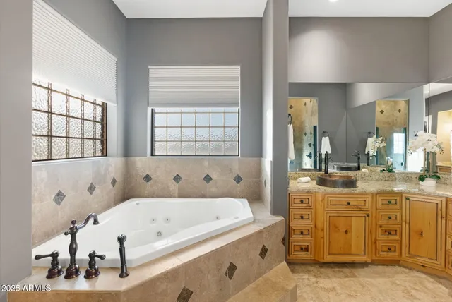 a bathroom with a tub a double vanity sink and mirror