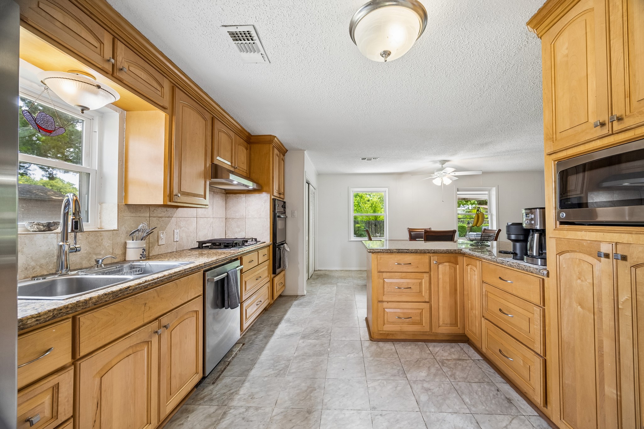 413 Mebane Lane Rosenberg, TX 77471 - Photo 15 of 30 This kitchen features wood cabinetry, granite countertops, and stainless steel appliances. It offers ample natural light with a window over the sink and has a spacious layout that flows into a dining area.