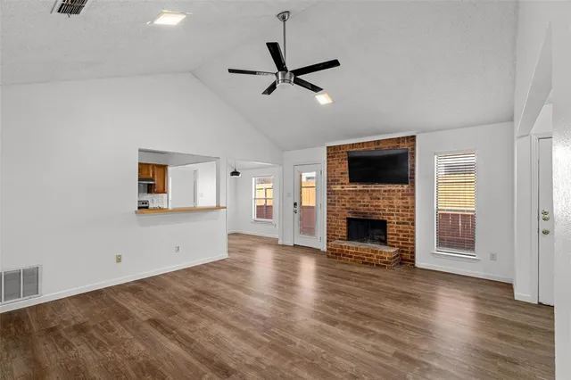 wooden floor in an empty room with a fireplace and a window