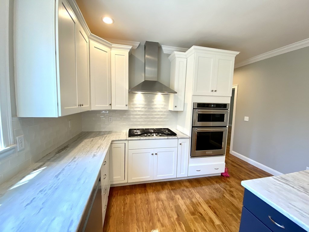 2 Littlefield Road Acton, MA 01720 - Photo 5 of 19 a kitchen with stainless steel appliances a stove a sink and white cabinets with wooden floor
