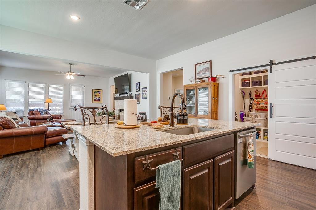 1328 San Marcus Drive Springtown, TX 76082 - Photo 9 of 37 Kitchen with dark brown cabinets, a barn door, light stone counters, dark wood finished floors, and recessed lighting