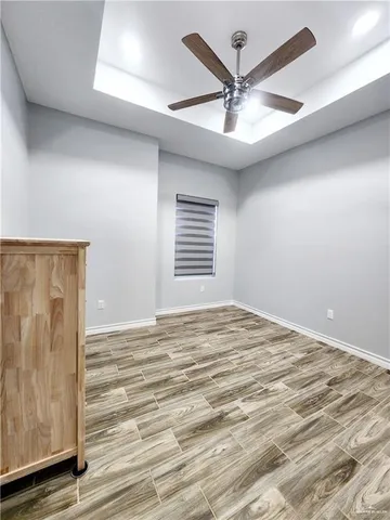 an empty room with wooden floor fan and windows