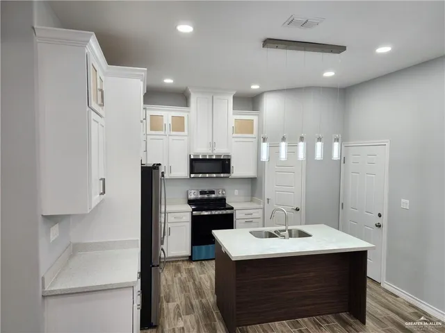 a kitchen with kitchen island a sink stainless steel appliances and cabinets