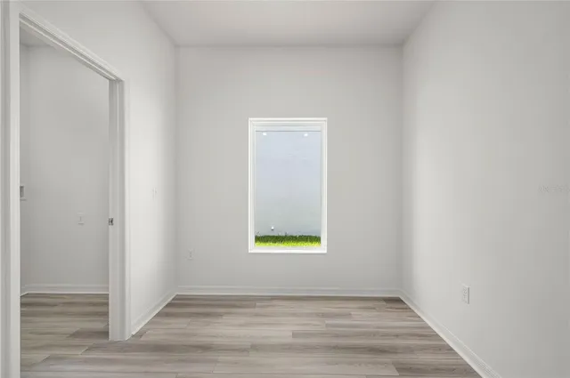 a view of an empty room with wooden floor and a window