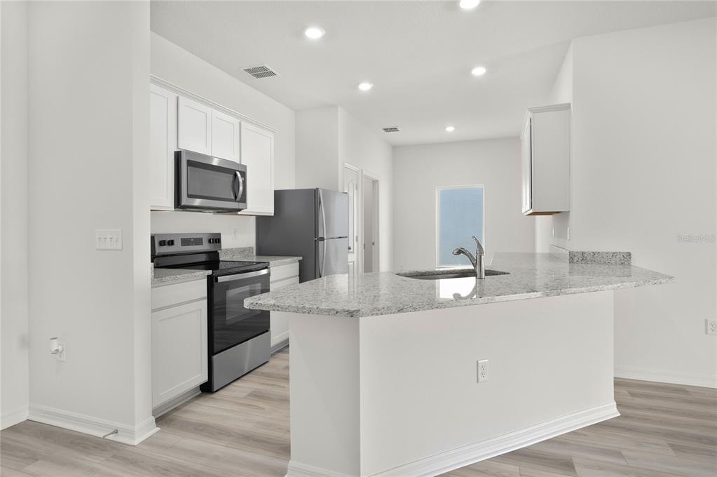 13284 Tula Loop Astatula, FL 34705 - Photo 3 of 24 a kitchen with stainless steel appliances granite countertop a sink a stove a refrigerator a microwave and cabinets